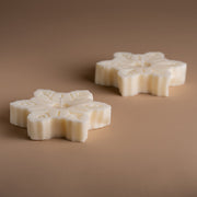 Two white snowflake-shaped candles on a beige background